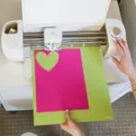 Overhead view of a cutting machine creating a heart shape on pink paper in California City.